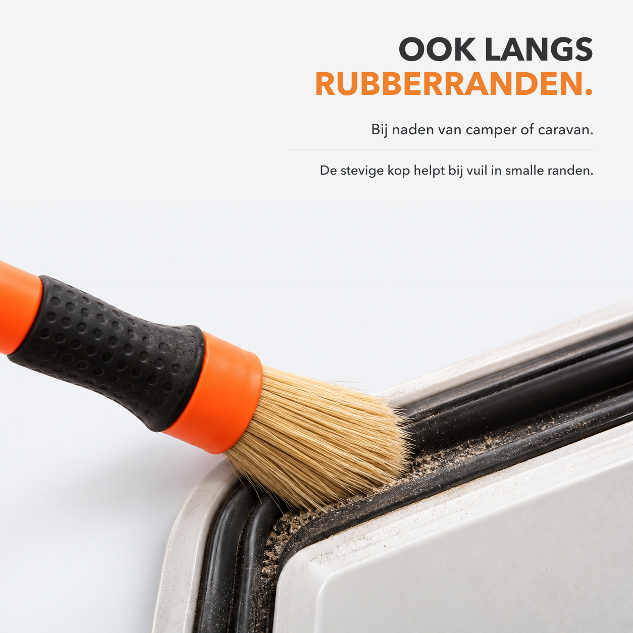 Stevige detailkwast haalt vuil uit de naad langs een rubberrand van camper of caravan