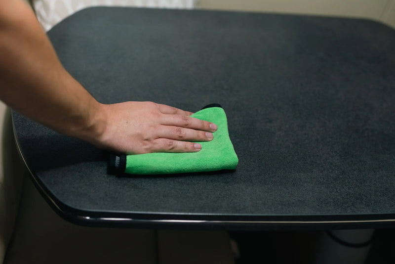 Tafelblad in camper schoonmaken met groene microvezeldoek en Carmotec Interieurreiniger