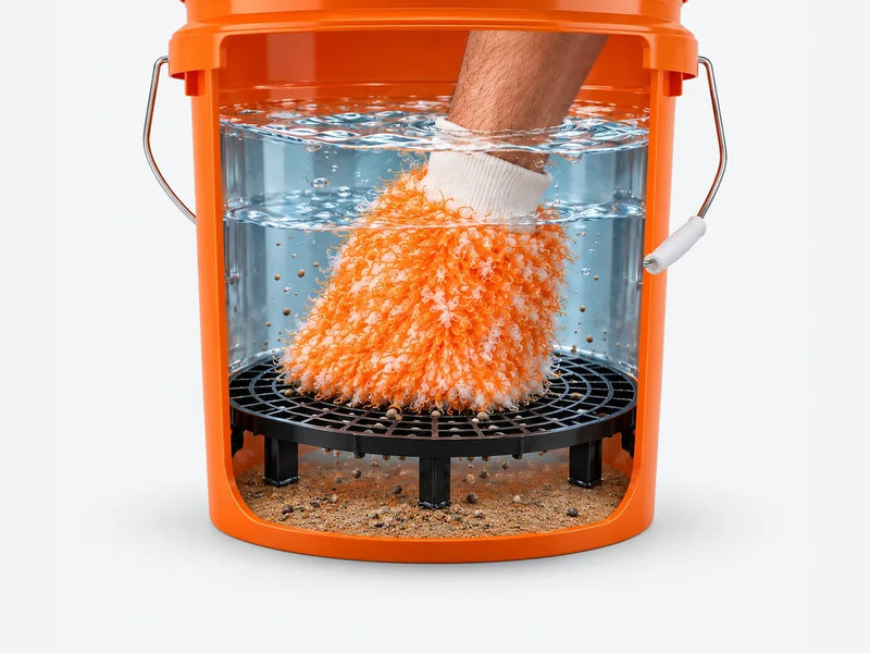 Washandschoen wordt uitgespoeld boven het vuilrooster; zand zakt onder de grid naar de bodem van de wasemmer